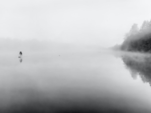 See im Nebel, in der Ferne ein Paddler