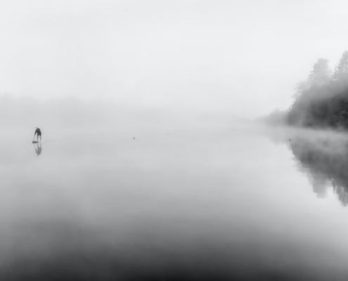 See im Nebel, in der Ferne ein Paddler